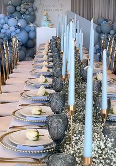 the table is set with blue candles and white plates, silver napkins and flowers