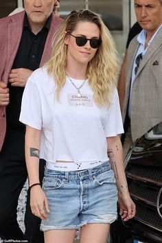 a woman in white shirt and jeans walking next to a man with sunglasses on her head