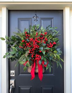 a christmas wreath on the front door of a house with red berries and greenery