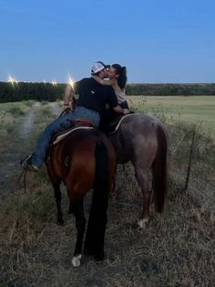 a man and woman riding on the back of a brown horse in an open field