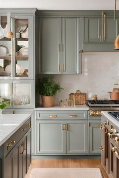 a kitchen with gray cabinets and gold pulls on the cupboards, white marble counter tops