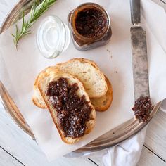 two pieces of bread with jam on them next to a knife and fork sitting on a napkin