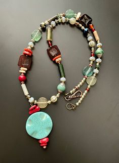 "Old and new come together in this stunning and eclectic holiday pendant necklace. Ancient Roman Glass beads nicely scattered with an eclectic mix of sparkle and color, including three modern red glass tile beads, all anchored with a light blue circular pendant.  This piece measures approx 25.5\" with two inch extension chain, finished with a decorative antique copper lobster claw clasp." Hippie Style Red Jewelry For Gift, Red Amulet Beaded Necklaces With Colorful Beads, Bohemian Czech Glass Pendant Beaded Necklace, Bohemian Turquoise Glass Necklaces, Handmade Eclectic Red Jewelry, Red Glass Bohemian Necklace, Handmade Red Hippie Beaded Necklace, Red Hippie Jewelry With Colorful Beads, Bohemian Turquoise Glass Necklace