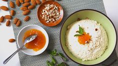 two bowls filled with food sitting on top of a table next to almonds and other foods