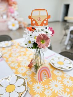 a vase filled with flowers sitting on top of a table next to plates and cups