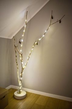 a white tree with lights on it in a room next to a box and wall