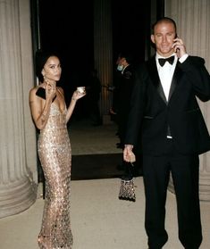 a man in a tuxedo talking on a cell phone next to a woman in a sequin dress