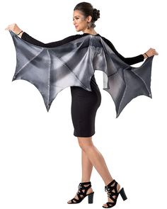 a woman in a black and silver costume with a bat cape on her shoulders, posing for the camera