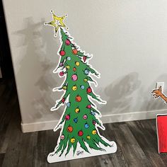 a christmas tree cut out on top of a wooden floor next to a red box