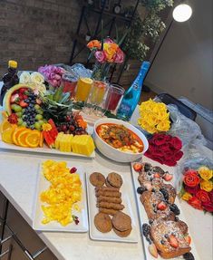 a table topped with plates and bowls filled with food next to flowers on top of a white counter