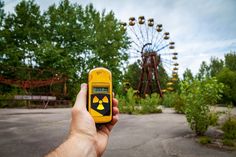 a person holding a yellow cell phone in front of a ferris wheel at an amusement park