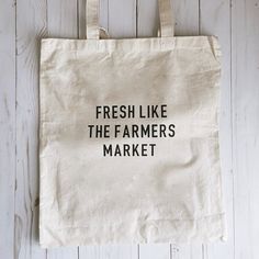 a tote bag that says fresh like the farmers market hanging on a white wooden wall