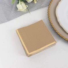 a table topped with plates and flowers next to a book on top of a table