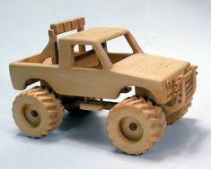 a toy truck made out of wood on a white surface with wheels and no tires