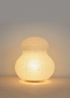 a white lamp sitting on top of a table next to a vase shaped like an egg