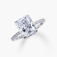 an engagement ring with a cushion cut diamond and pave set diamonds on the sides