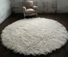 a chair sitting on top of a wooden floor in front of a white round rug