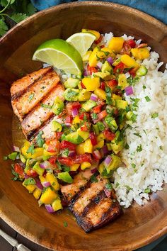 a wooden bowl filled with rice and meat next to a slice of lime on top of it