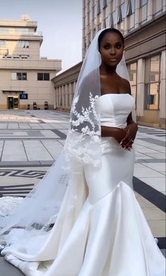 a woman in a wedding dress standing on the street