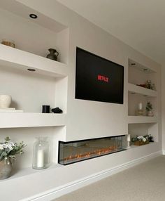 a television mounted on the wall above a fireplace with candles and flowers in vases