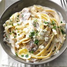 a bowl filled with pasta and meat covered in sauce on top of a white table cloth