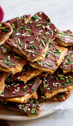 a white plate topped with chocolate and sprinkles covered pretzel cookies