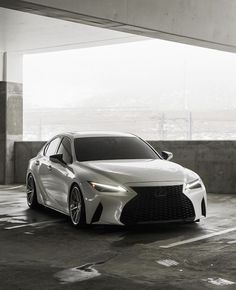 a white sports car parked in an empty parking lot next to a concrete wall and floor