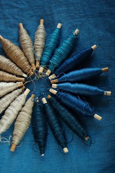 several spools of thread are arranged in a circle on a blue tablecloth