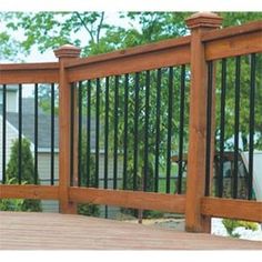 a wooden deck with wrought iron railings and trees in the background