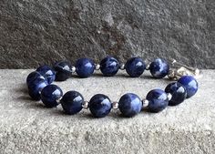 IndigoLayne, handcrafted AAA Blue Sodalite bracelet.   100 % natural untreated in any way, denim blue stones with white Matrix,  8 mm, inter-spaced with dainty silver bead.  Strong multi- strand jewelers wire, closes with a 925 sterling toggle and ring. Perfect for everyday wear, these bracelets are super comfortable and meant to be enjoyed often. They also make a fabulous gift! Rock Lore & Tidbits... Sodalite, a rich royal blue mineral, is a common constituent of lapis lazuli. It is said that sodalite will harmonize the inner being and bring order to conscious mind. Arrives gift wrapped in our IndigoLayne signature box. © Sissy Altom All rights reserved. Images may not be reproduced, resold or used without written consent. *Artist Copyright does not transfer with the purchase of an origin Sodalite Round Beads Bracelets As Gifts, Sodalite Bead Bracelets As Gift, Sodalite Beaded Bracelets With Natural Stones For Gift, Sodalite Round Beads Bracelets For Healing, Spiritual Sodalite Gemstone Beaded Bracelets, Handmade Sodalite Round Bead Bracelets, Sodalite Bracelet, Stone Stacking, Inner Being