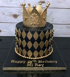 a black and gold birthday cake with a crown on top