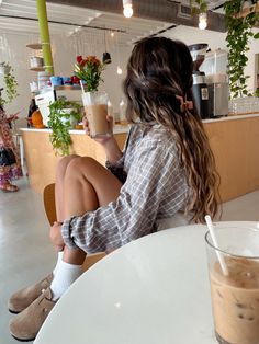 a woman sitting at a table with a drink in her hand