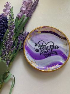 purple flowers are sitting next to a glass plate