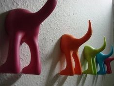 three different colored plastic dinosaurs are hanging on the wall next to each other in a row