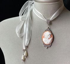 Peach Cameo Necklace!Perfect for any occasion!!A soft peach cameo set in an antique silver pendant and attached to a light cream organza ribbon....I have added 2 light cream teardrop pearls to the end of each tie....The perfect gift for that very special lady or teen.....Please select if you would like this item gift wrapped.....I will also include a quality card with your special message.....Thank you for taking time to browse my shop “Veronica Rose Designs” Luxury Cameo Necklace For Formal Events, Elegant Cameo Jewelry For Wedding, Elegant Cameo Necklace For Formal Occasions, Elegant Cameo Necklaces For Wedding, Elegant Cameo Necklace For Wedding, Vintage Cameo Jewelry For Wedding, Elegant Cameo Jewelry For Vintage Events, Elegant Cameo Necklace For Vintage Events, Elegant Oval Cameo Necklace For Wedding