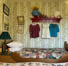 two beds in a room with wallpaper and pictures on the wall above them,