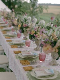 a long table with plates and vases filled with flowers