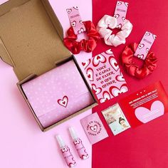 the contents of a valentine's day gift box are laid out on a pink and red background