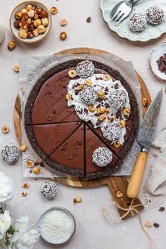 there is a chocolate pie on the table with nuts and other desserts around it