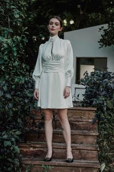 a woman in a white dress standing on some steps