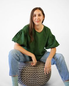 a woman is sitting on top of a round ottoman with her hands in her pockets