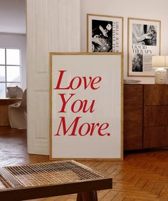 there is a sign that says love you more on the wall next to a table