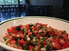 a white bowl filled with lots of food on top of a table