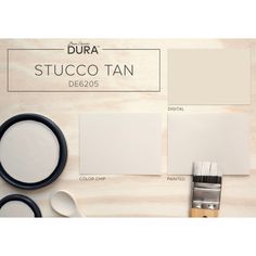 some white paint and brushes on top of a wooden table with the words dura stucco tan