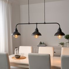 a dining room table with four lights hanging over it