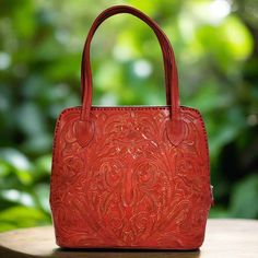 This stunning hand-tooled leather bag in a vibrant red color is a true statement piece. Handmade  with love and care by talented artisans. Each detail of the bag has been meticulously handcrafted by skilled artisans, creating a unique and one-of-a-kind design.   Add a pop of color to your outfit with this exquisite hand-tooled leather handbag. height:29 cm.  11 1/2 inches width at the bottom: 30cm.  12-inches base:12.5 cm.  5 inches straps: 21cm    8 inches interior: suede leather zippered at th Artisan Red Shoulder Bag For Everyday Use, Artisan Red Tote Shoulder Bag, Hand Tooled Red Rectangular Bag, Red Hand Tooled Rectangular Bag, Red Hand-tooled Rectangular Bag, Artisan Red Rectangular Shoulder Bag, Red Hand Tooled Bag For Daily Use, Artisan Red Bag For Daily Use, Artisan Red Leather Bags