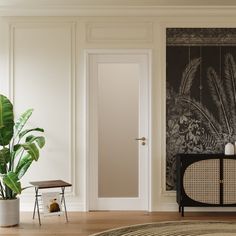 a living room with white walls and wooden flooring next to a potted plant