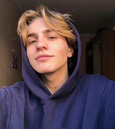 a young man with blonde hair wearing a blue hoodie