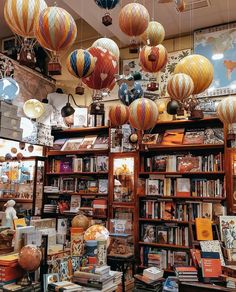 many colorful lanterns hanging from the ceiling in a room with bookshelves and other items