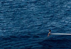 a person sitting on the edge of a boat in the middle of the ocean,